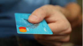 A close up of a left hand presenting a blue credit card as if to pay - Burton accountants Alexander Accountancy