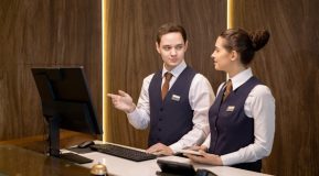 two young people male and female behind a hotel reception desk