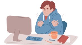 Illustration of a man sitting at a desktop PC in a blue hoody shivering in a cold workplace