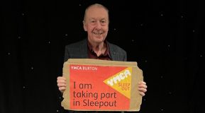 Picture of David Alexander holding up a YMCA Burton Sleepout 2024 poster saying I'm taking part - David Alexander Just Giving YMCA Burton