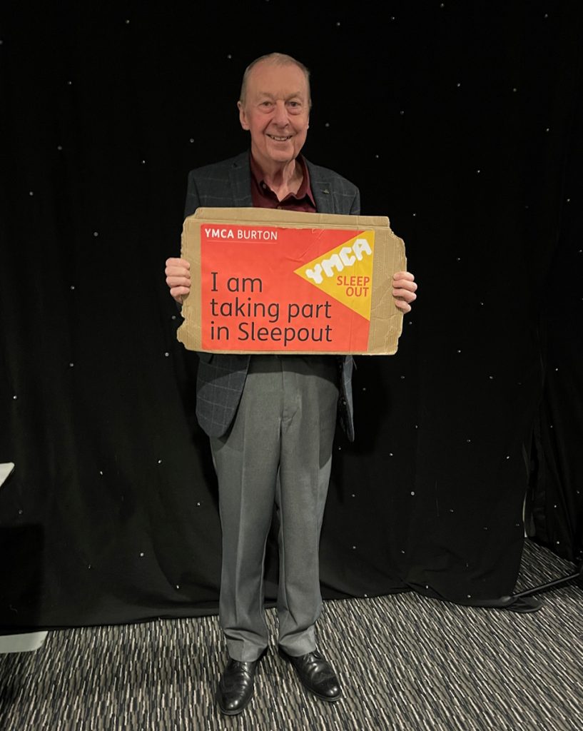 Picture of David Alexander holding up a YMCA Burton Sleepout 2024 poster saying I'm taking part